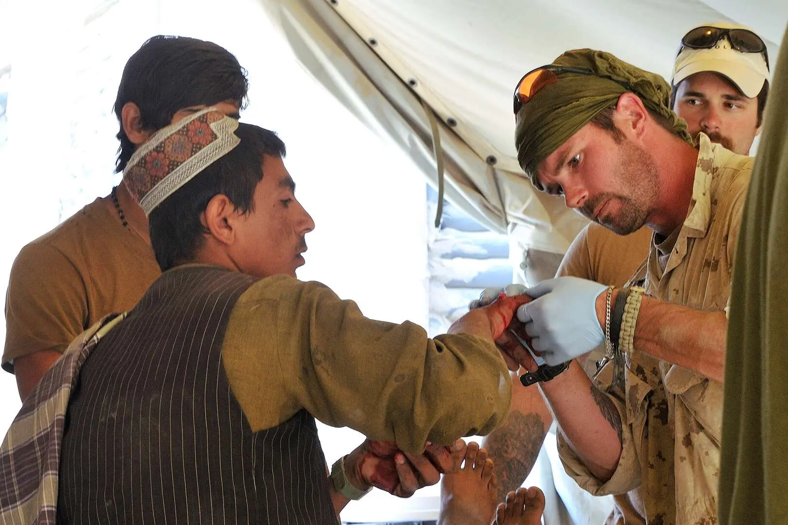 Le caporal Mike Gadway soigne la main ensanglantée d’un villageois afghan dans une tente de l’armée.