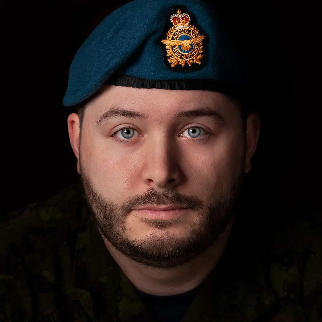 Sur un fond noir, on voit le caporal Christian Turcotte portant le béret bleu de l’Aviation royale canadienne. Son visage est ovale avec des yeux bleus très clairs et affiche une légère barbe.