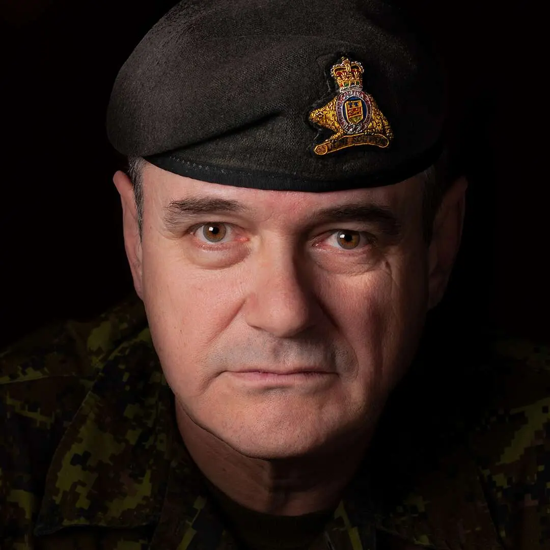 Sur un fond noir, le major Noël Dufresne regarde la caméra avec un air sévère. Cet homme au visage carré porte le béret vert du Royal 22ième Régiment.