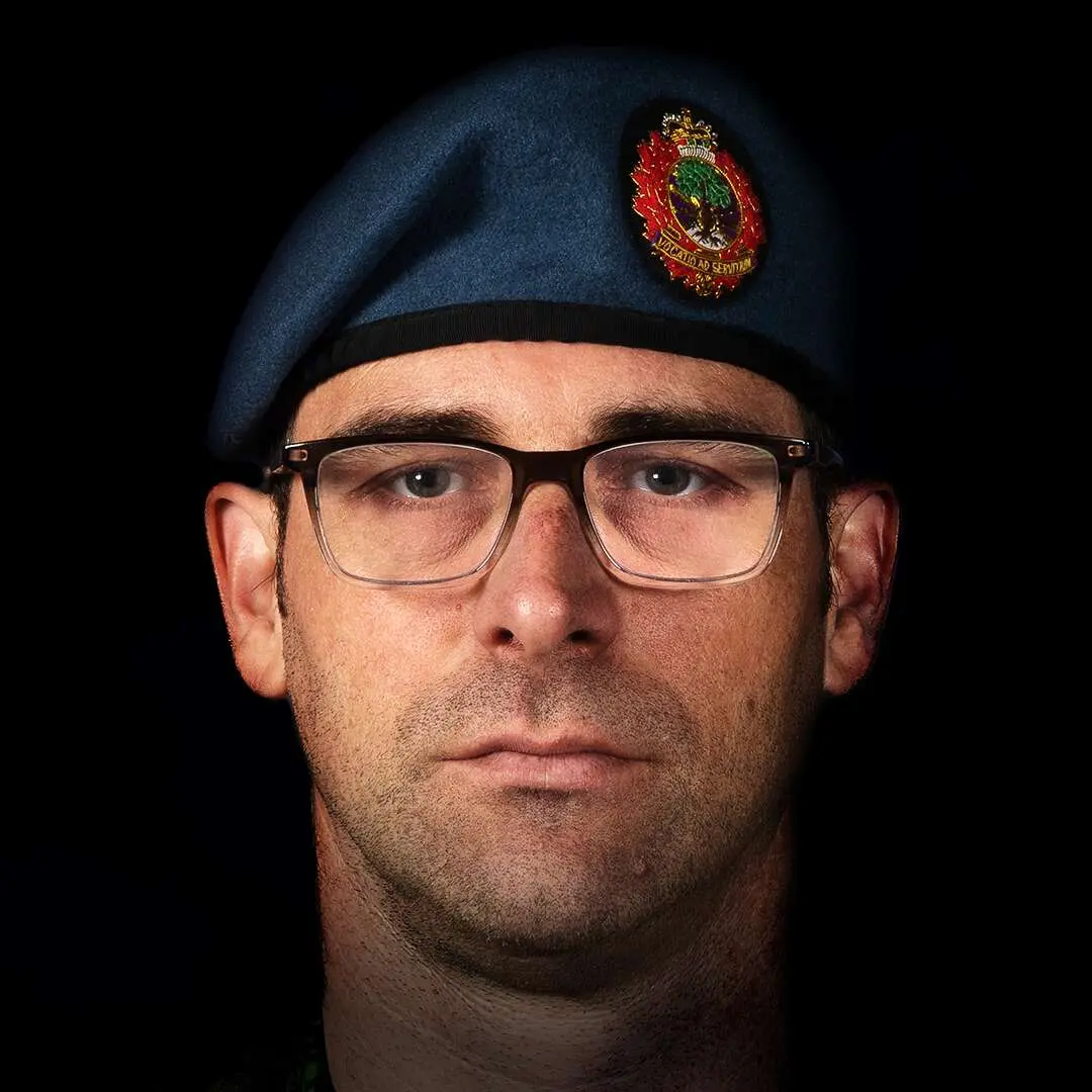 Portant le béret bleu de l’Aviation royale canadienne et des lunettes à monture noire, le capitaine Beauchemin a le visage ovale et affiche une barbe de trois jours. Il fixe la caméra avec un air impassible.