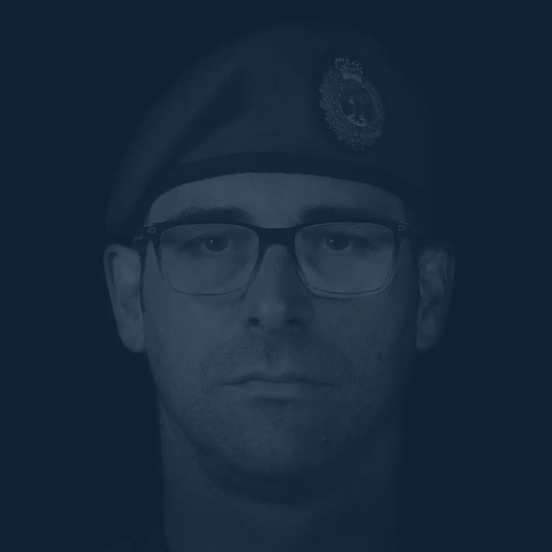 Portant le béret bleu de l’Aviation royale canadienne et des lunettes à monture noire, le capitaine Beauchemin a le visage ovale et affiche une barbe de trois jours. Il fixe la caméra avec un air impassible.