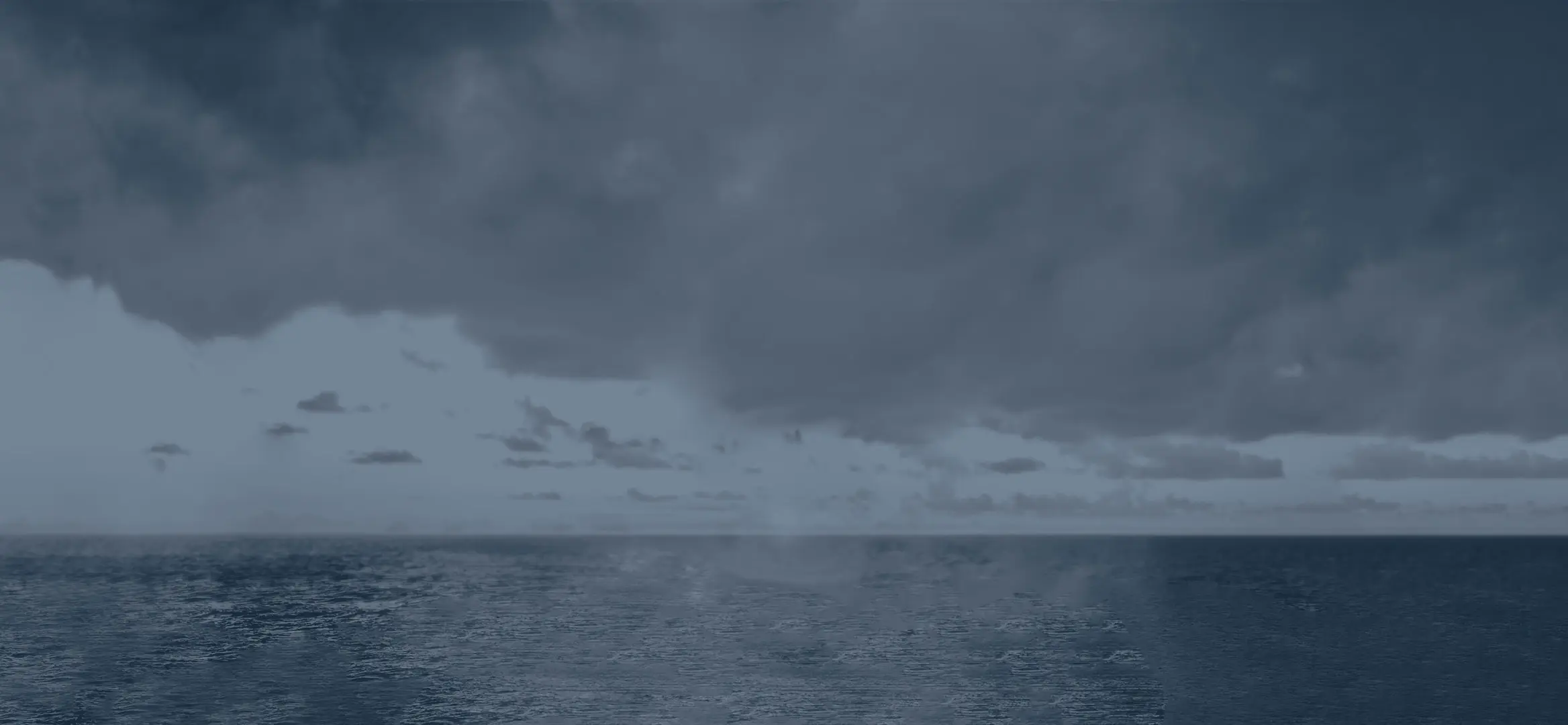 Un hélicoptère est stabilisé au-dessus du pont d’un navire. Trois militaires sont en position sous l’appareil afin de réaliser un exercice de treuillage. En toile de fond, on peut voir le ciel parsemé de nuages et le soleil orangé qui s’apprête à plonger dans la mer aux reflets gris-mauve.